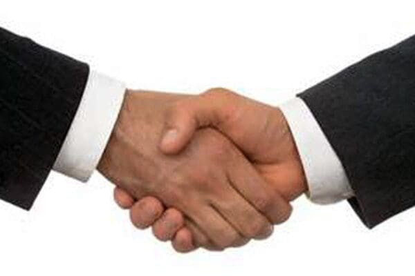 Close-up of two hands in a hand shake. Cuffs of white shirt under black jackets visible.